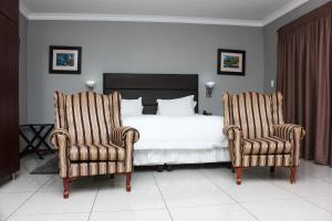 a bedroom with a bed and two chairs at Vahlavi Lodge in Giyani