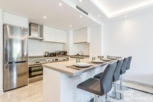 kuchnia z blatem z krzesłami i lodówką w obiekcie LetsMarbella - NEW 2BR APARTMENT IN PUERTO BANUS - POOL & PARKING w Marbelli