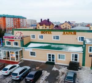 a hotel with cars parked in a parking lot at Hotel Дар-Ай in Kostanay