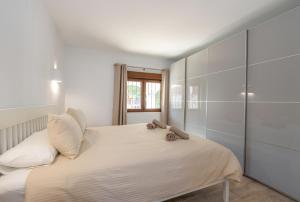 een slaapkamer met een bed met witte lakens en een raam bij Casa Colina in Jávea