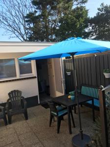 een blauwe paraplu op een tafel en twee stoelen bij Mikasabeach in Zandvoort