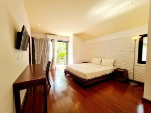 a bedroom with a bed and a desk and a window at Coconut Beach Resort in Lamai