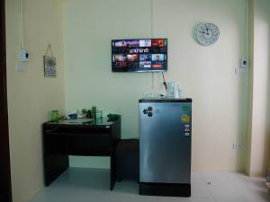 a refrigerator in a room with a desk and a clock at C&TApartment in Ban Thai Don (1)