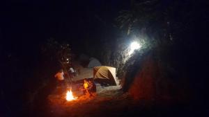 a person standing next to a camp fire at night at Nature river camp in Madikeri