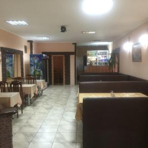 a restaurant with tables and couches and tables and chairs at Hotel Дар-Ай in Kostanay