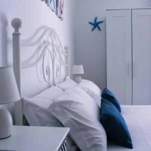 a white bed with white sheets and blue pillows at Il Fungo di Lacco in Ischia