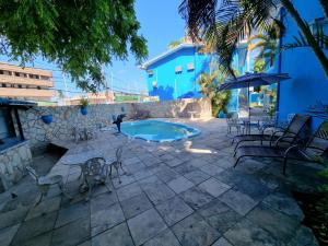 a patio with a pool and chairs and an umbrella at Pousada Morada Azul in Porto De Galinhas
