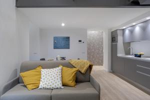 un soggiorno con divano grigio e cuscini gialli di Suite Roma - by MyHomeInComo a Como