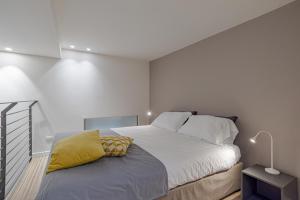 una camera bianca con un grande letto con un cuscino giallo di Suite Roma - by MyHomeInComo a Como