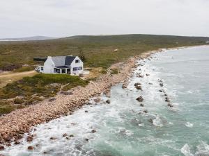 uma casa branca na costa de um corpo de água em Kanon Private Nature Reserve em Mossel Bay