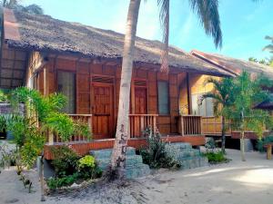 a house with a palm tree in front of it at JJS BACKPACKERS VILLAGE in Siquijor