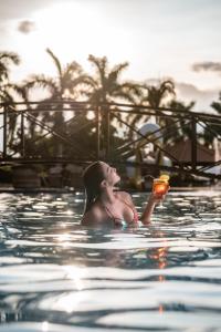 Obbá Coema Village Hotel في كابيتوليو: وجود امرأة تمسك الشراب في المسبح