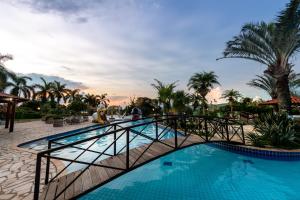uma ponte sobre uma piscina num resort em Obbá Coema Village Hotel em Capitólio