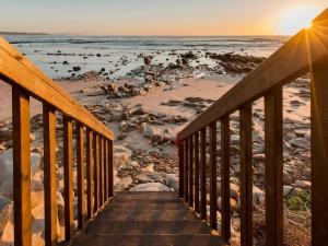 a wooden staircase leading to a beach with the ocean at Kanon Private Nature Reserve in Mossel Bay