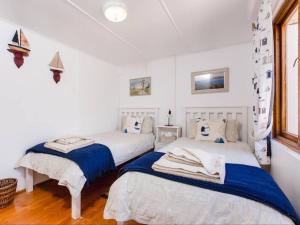 two beds in a room with white walls and wood floors at Kanon Private Nature Reserve in Mossel Bay