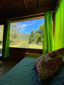 a bedroom with a window with a green curtain at Riberas del Azul in Lago Puelo