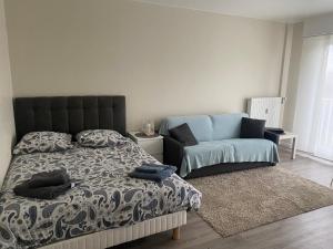 ein Schlafzimmer mit einem Bett und einem Sofa in der Unterkunft Appartement Parc de Fresnoy in Roye