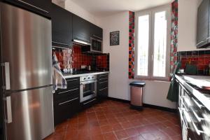 uma cozinha com armários pretos e um frigorífico de aço inoxidável em Micoulet, Parking - Clim em Arles