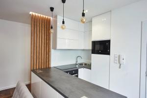a kitchen with white cabinets and a black counter top at Beautiful apartment near the city center in Košice