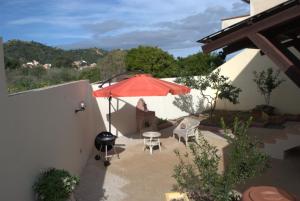 un patio con sombrilla, sillas y parrilla en ELAIA HOUSE, en Capoterra