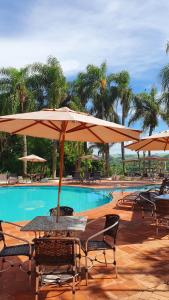 een tafel en stoelen met parasols naast een zwembad bij Panorama Park Hotel in Igarassú