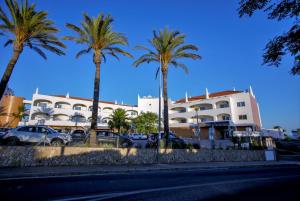 eine Gruppe von Palmen vor einem Gebäude in der Unterkunft Hotel Maritur - Adults Only in Albufeira