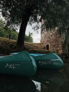 dos barcos sentados en el agua junto a un árbol en Vintage tent at the Lovsin Estate, en Metlika