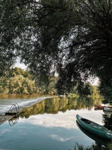 einen Fluss mit einem grünen Boot im Wasser in der Unterkunft Vintage tent at the Lovsin Estate in Metlika