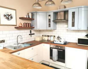 a kitchen with white cabinets and a sink at The Coach House Apartment at Cefn Tilla Court, Usk in Usk