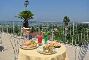 una mesa con platos de comida en la parte superior de un balcón en Hotel Le Pinede Vistamare, en Pozzuoli