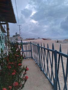 une clôture bleue à côté d'une plage avec une sandyermott dans l'établissement Pousada Pôr do Sol - Galinhos, à Galinhos