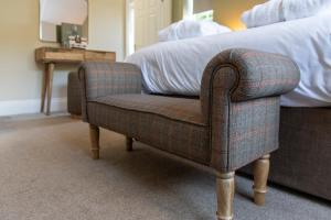 a chair sitting in a bedroom with a bed at Ye Old Ferrie Inn in Symonds Yat
