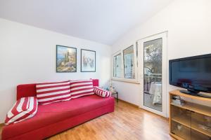 ein Wohnzimmer mit einem roten Sofa und einem Flachbild-TV in der Unterkunft Apartmani Toni in Podaca