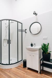 łazienka z przeszkloną kabiną prysznicową i umywalką w obiekcie Podzamcze 24 Apartments w Krakowie