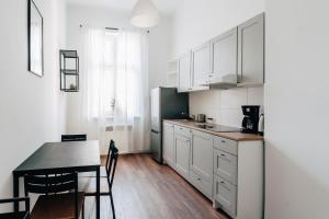 kuchnia z białymi szafkami i stołem oraz jadalnia w obiekcie Podzamcze 24 Apartments w Krakowie +37 zdjęć