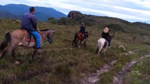 a group of people riding horses in a field at Pousada Esquina de Lavras in Lavras Novas