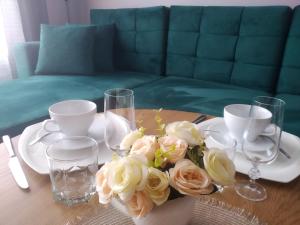 una mesa con un jarrón de flores y vasos. en Baltijos 12b Apartamentai, en Klaipėda