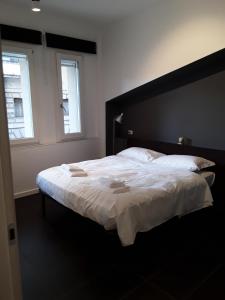 a bedroom with a large bed with white sheets and two windows at SAVOIA ROOMS in Padova