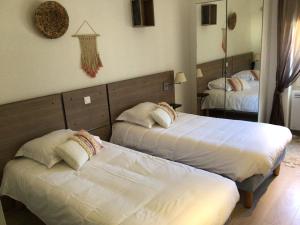 a hotel room with two beds and a mirror at Hôtel Restaurant de Londres in Saint-Just-en-Chevalet