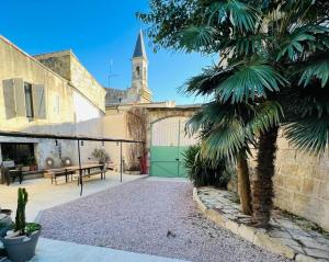 a palm tree in front of a building with a green garage at Oustaou de Betty et Bob in Le Cailar
