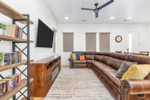 a living room with a brown leather couch and a tv at Villa 13, 4 BEDROOM NEW LISTING! STUNNING! YEAR ROUND HEATED POOL & HOT TUB! in St. George