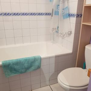 La salle de bains est pourvue d'une baignoire blanche et de toilettes. dans l'établissement GITE MAEN ROCH, à Antrain