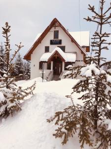 um edifício coberto de neve com árvores em primeiro plano em Velo Apartamenty em Czorsztyn