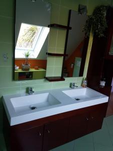 La salle de bains est pourvue d'un lavabo blanc et d'un miroir. dans l'établissement Charmante chambre d'hôtes en Normandie, à Valognes