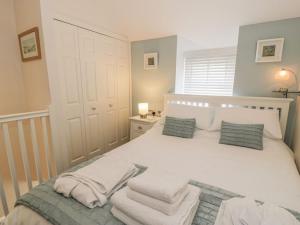 a bedroom with a white bed with towels on it at Kirrin Cottage in Conwy