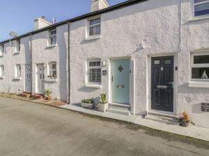 a white building with a blue door on a street at Kirrin Cottage in Conwy