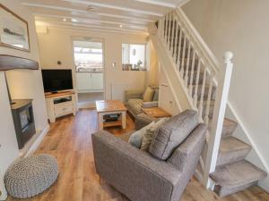 a living room with a couch and stairs with a television at Kirrin Cottage in Conwy