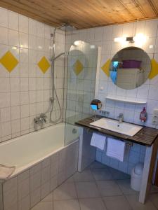 a bathroom with a tub and a sink and a mirror at Landhaus Alpenstern in Riezlern +30 photos