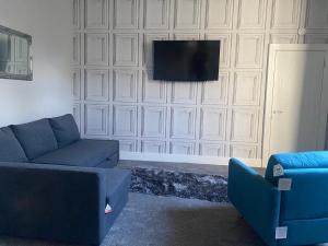 een woonkamer met een bank en een tv aan de muur bij Town Centre Holiday Let in Hawick