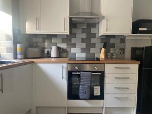 a kitchen with white cabinets and a stove at Town Centre Holiday Let in Hawick
